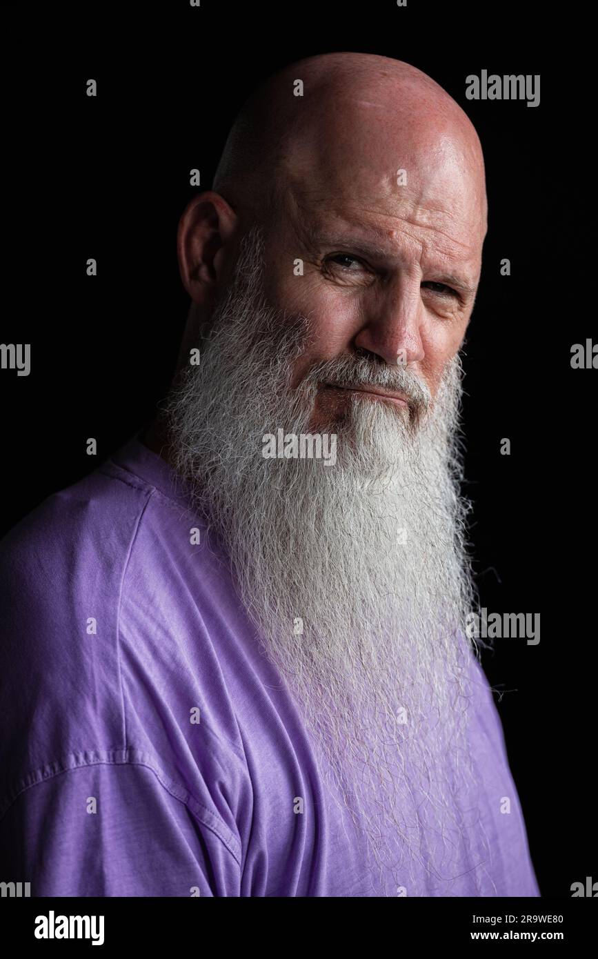 Portrait of man with long gray beard wearing purple t-shirt close-up headshot Stock Photo