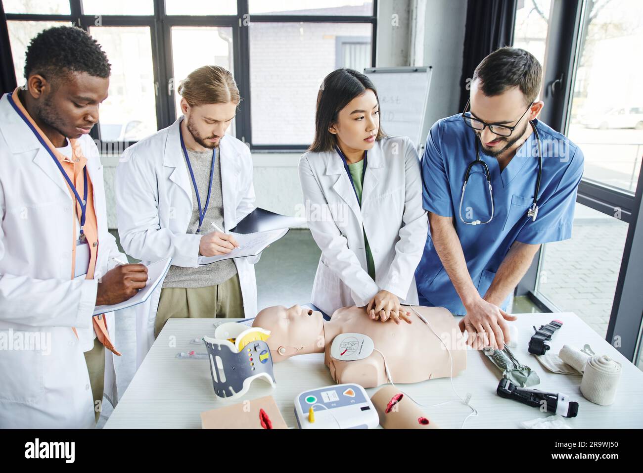Medical Instructor multiethnic students in white coats writing in notebooks near medical ...
