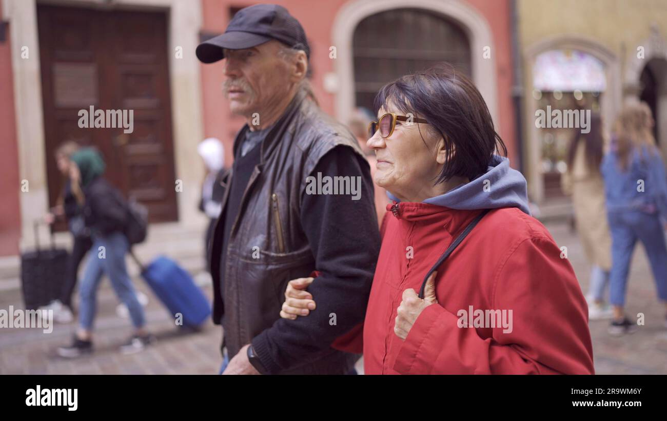 Elderly couple of tourists are walking through the historical center seeing the sights in an old European city. Palace Square, Warsaw Old Town Stock Photo