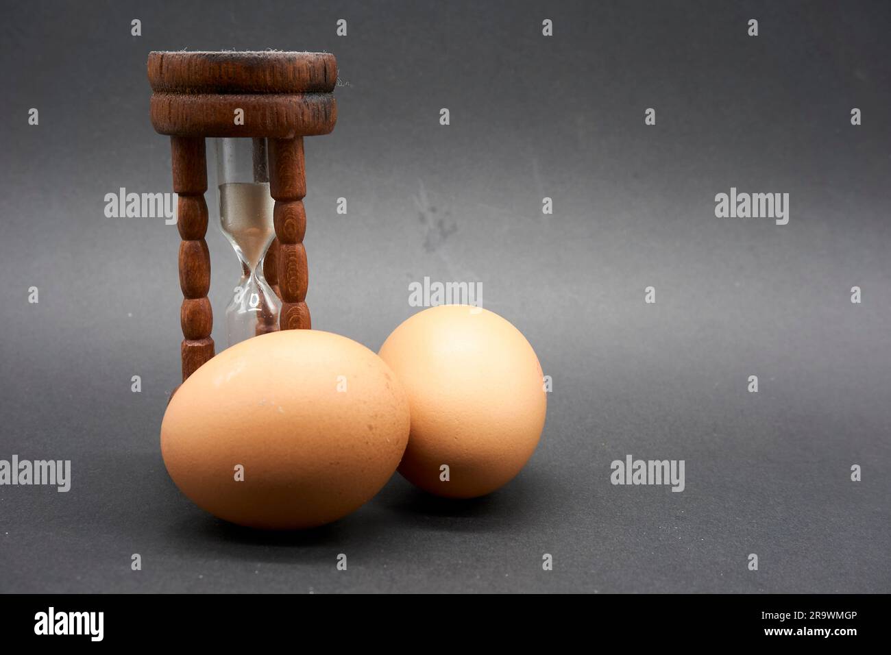 Close up of an Antique Hourglass Egg timer with a couple of Eggs Stock Photo