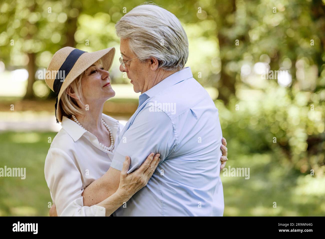 Happy elderly couple dressed in summer hugging in park, Cologne, North Rhine-Westphalia, Germany Stock Photo