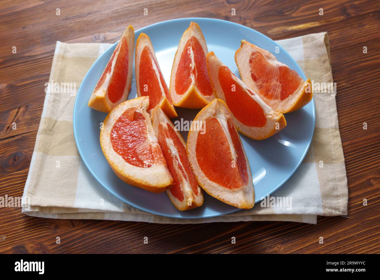 Cutting ripe grapefruit on board flat lay. Citrus fruits, making fresh juice or tropical cocktails Stock Photo