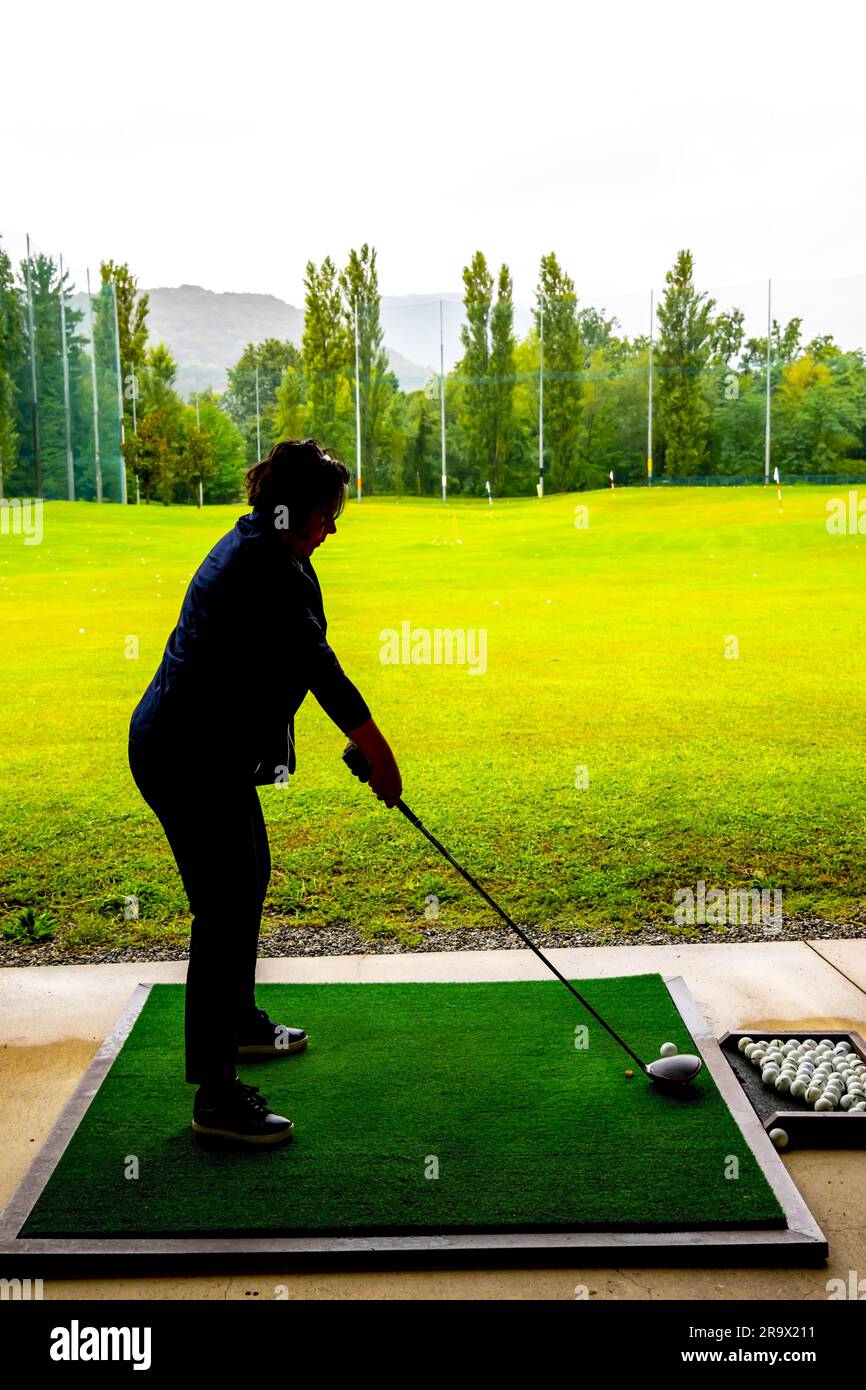 Golfer Training Her Golf Club Driver on Driving Range in a Rainy Day in