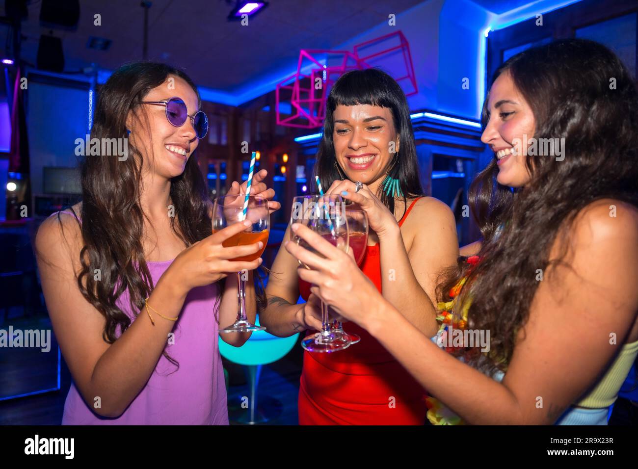 Portrait attractive women toasting and having fun with drinks in disco club at summer night party in pub Stock Photo