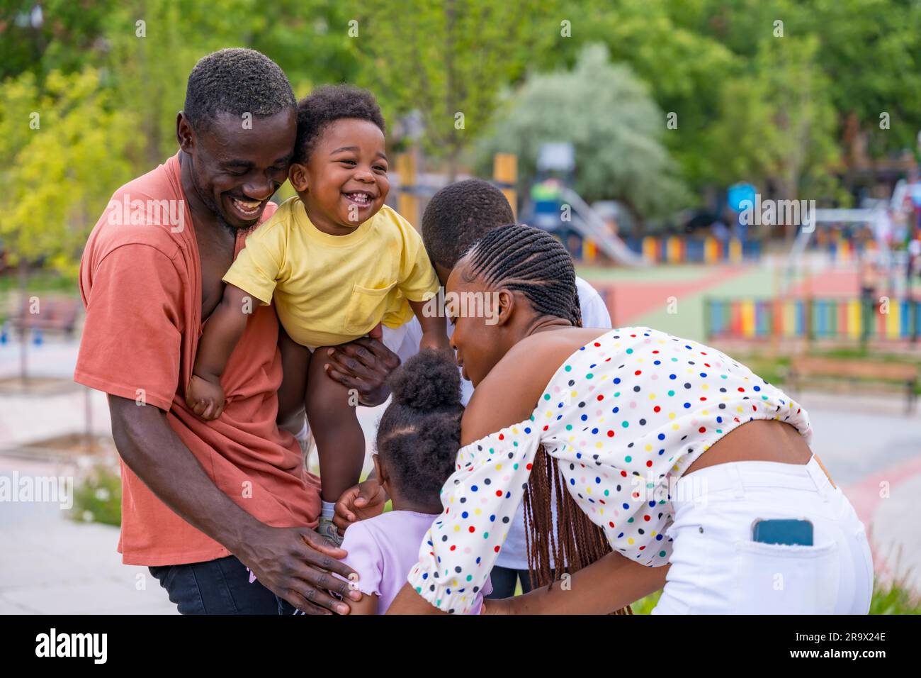 African black ethnic family with children in playground, hugging after school Stock Photo