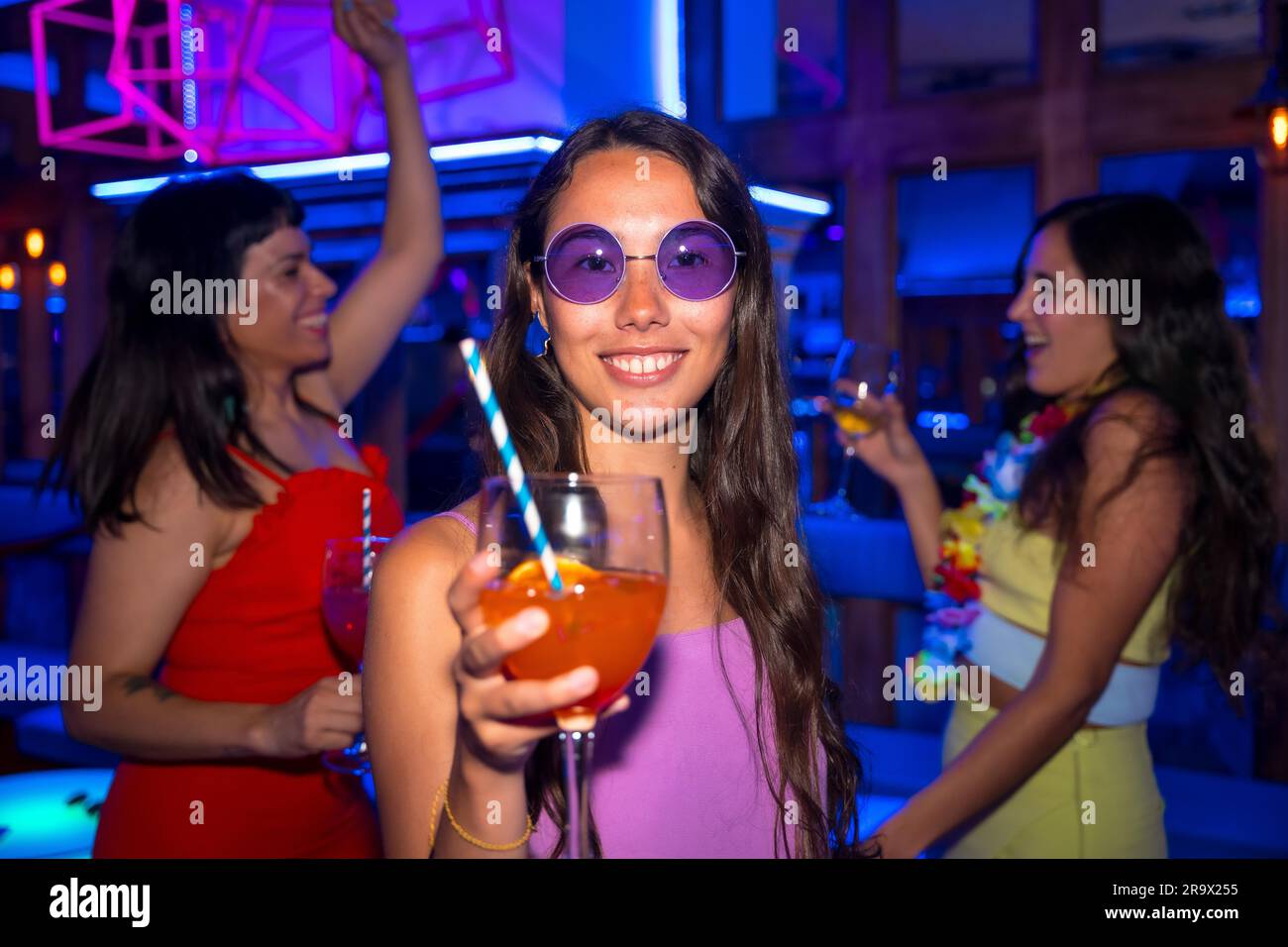 Portrait attractive woman toasting and having fun with a glass of alcohol in a nightclub at a night party Stock Photo