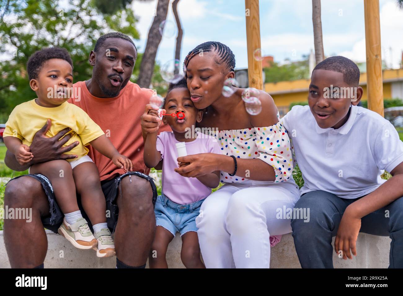 African black ethnic family with children in playground blowing soap bubbles Stock Photo