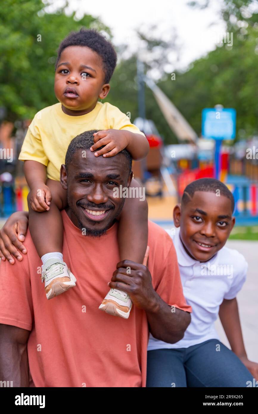 Portrait of African black ethnicity father with his children in the playground of the city park Stock Photo