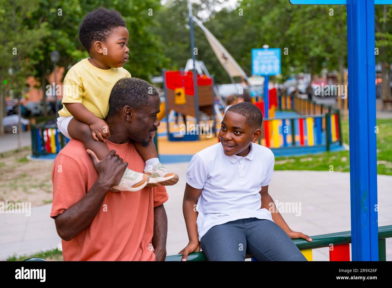 African black ethnicity father talking with his children in the playground of the city park Stock Photo