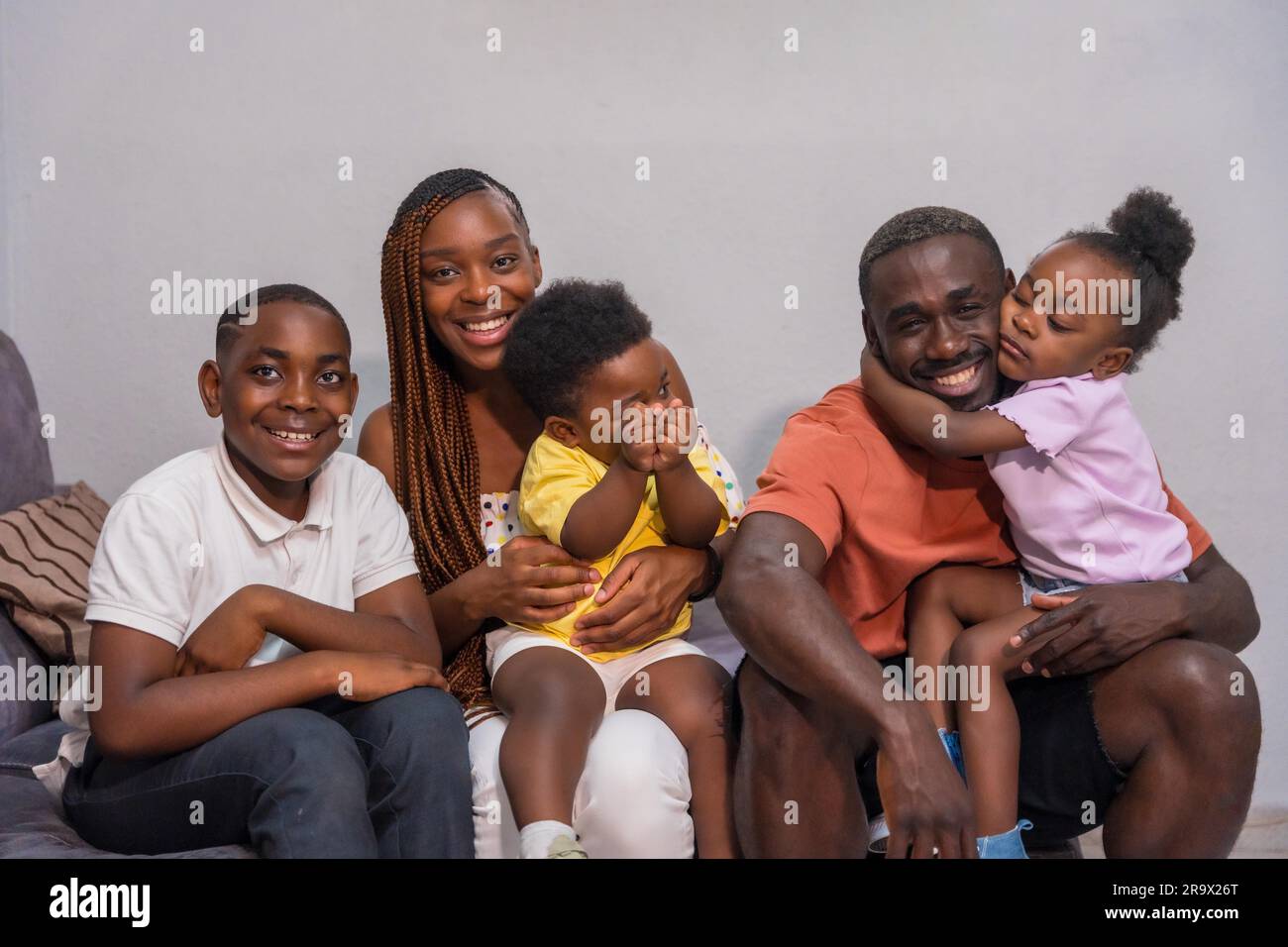 Portrait of black African ethnicity family with children on the sofa at home having fun Stock Photo