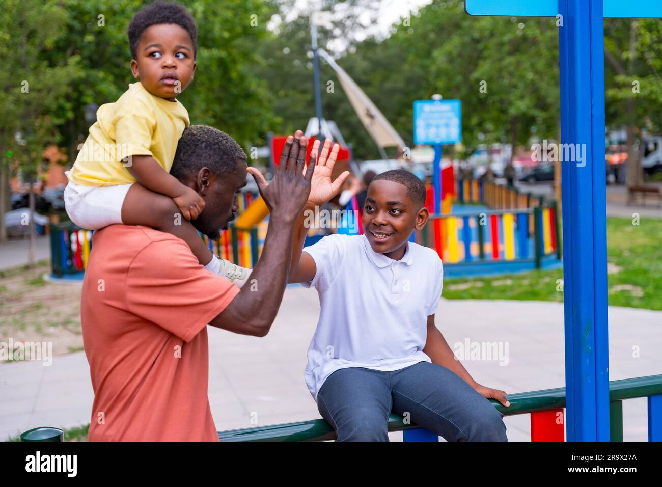 African black ethnicity father waving with his children in the playground of the city park Stock Photo