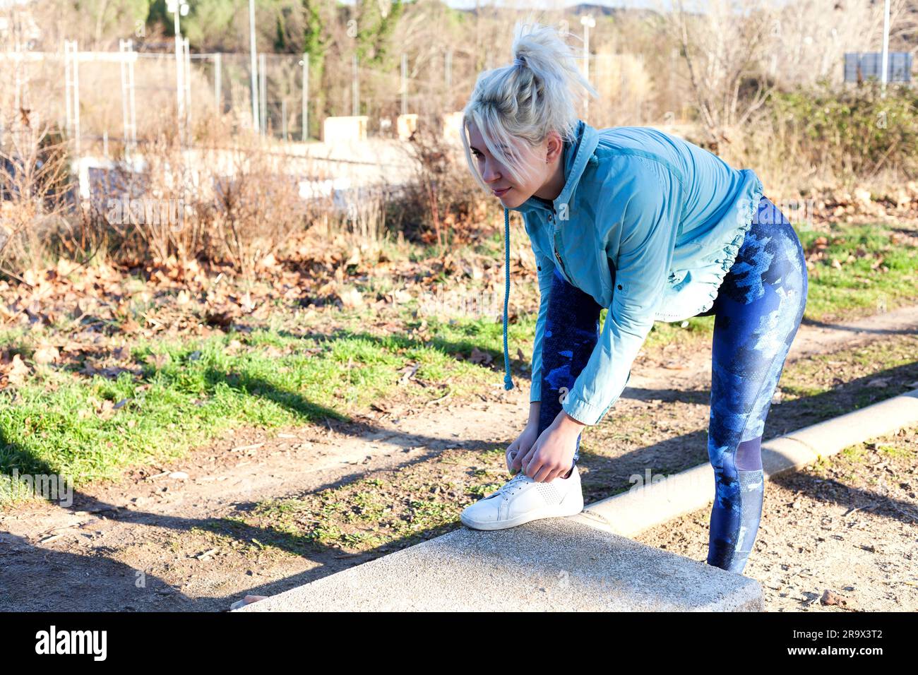 Young blonde woman tying her running shoes before a run Stock Photo