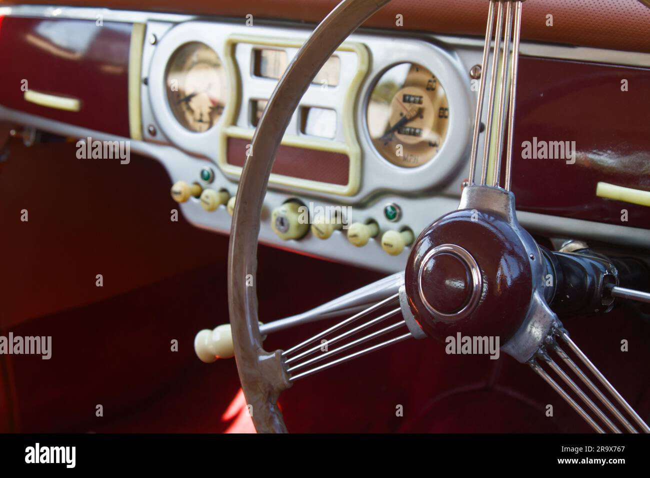 The Mauve, Burgundy Steering Wheel And Plastic Dashboard Instrument Panel Of A 1950 Austin A90 Atlantic Retro Motor Vehicle Automobile, England UK Stock Photo