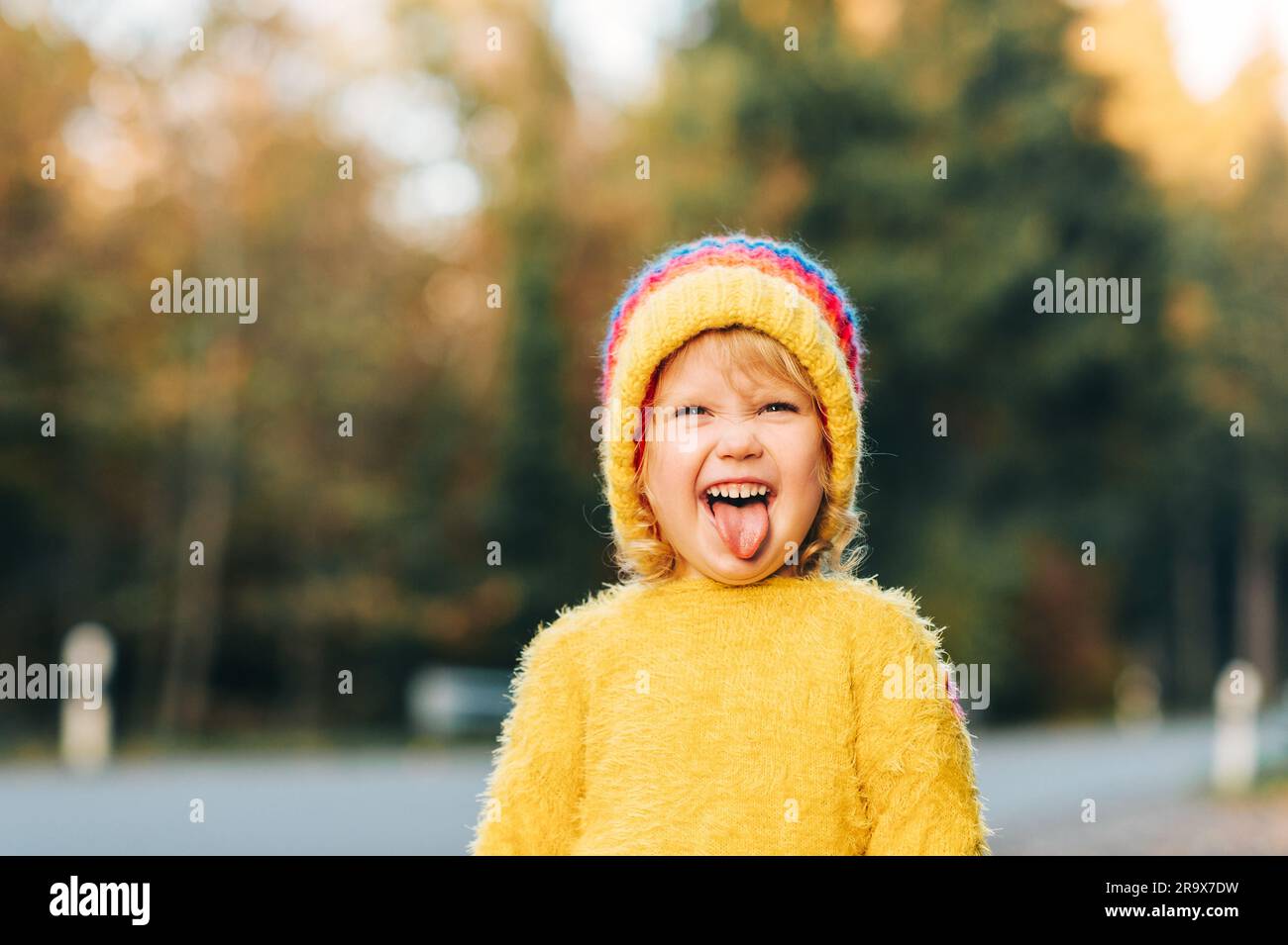 Outdoor portrait of cute toddler girl wearing yellow hat and pullover Stock Photo