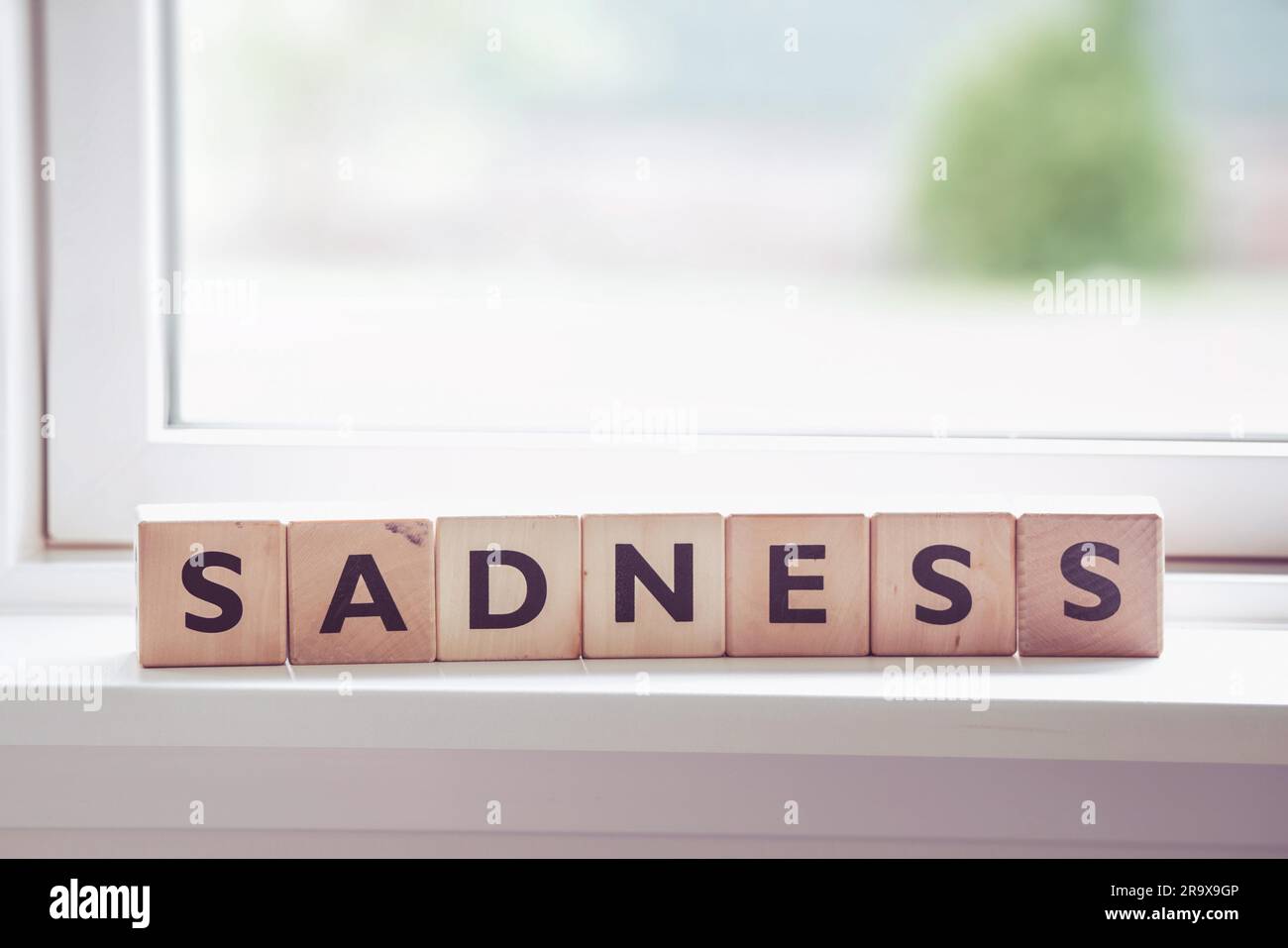 Sadness word made of wood in a bright window Stock Photo