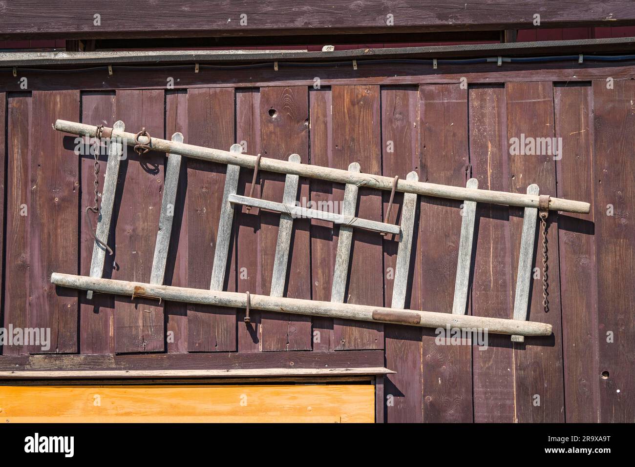 Wooden ladder hanging on the wall of a shed in the country Stock Photo