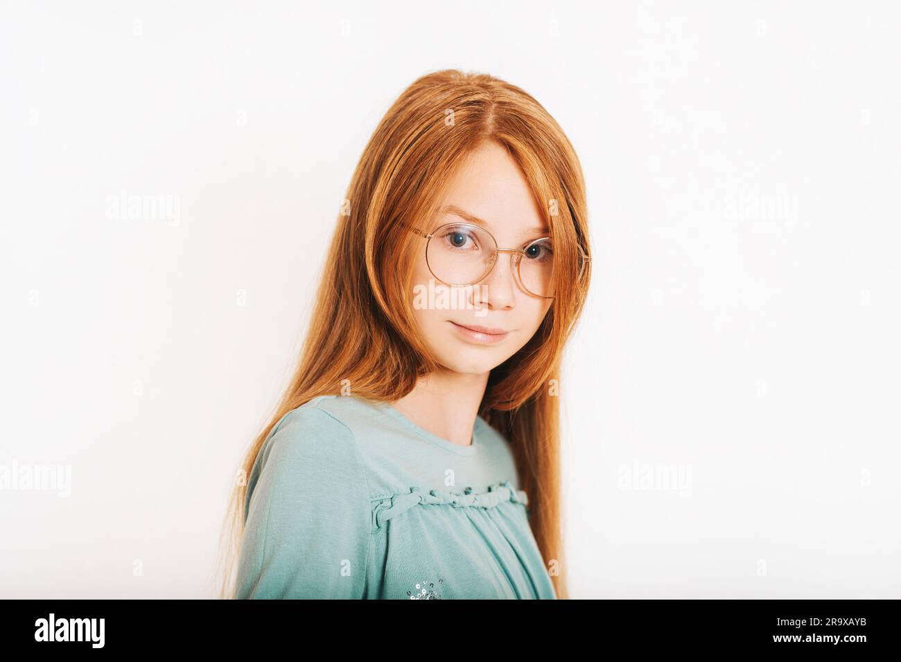 Studio shot of young preteen red-haired girl against white background, wearing eyeglasses Stock Photo