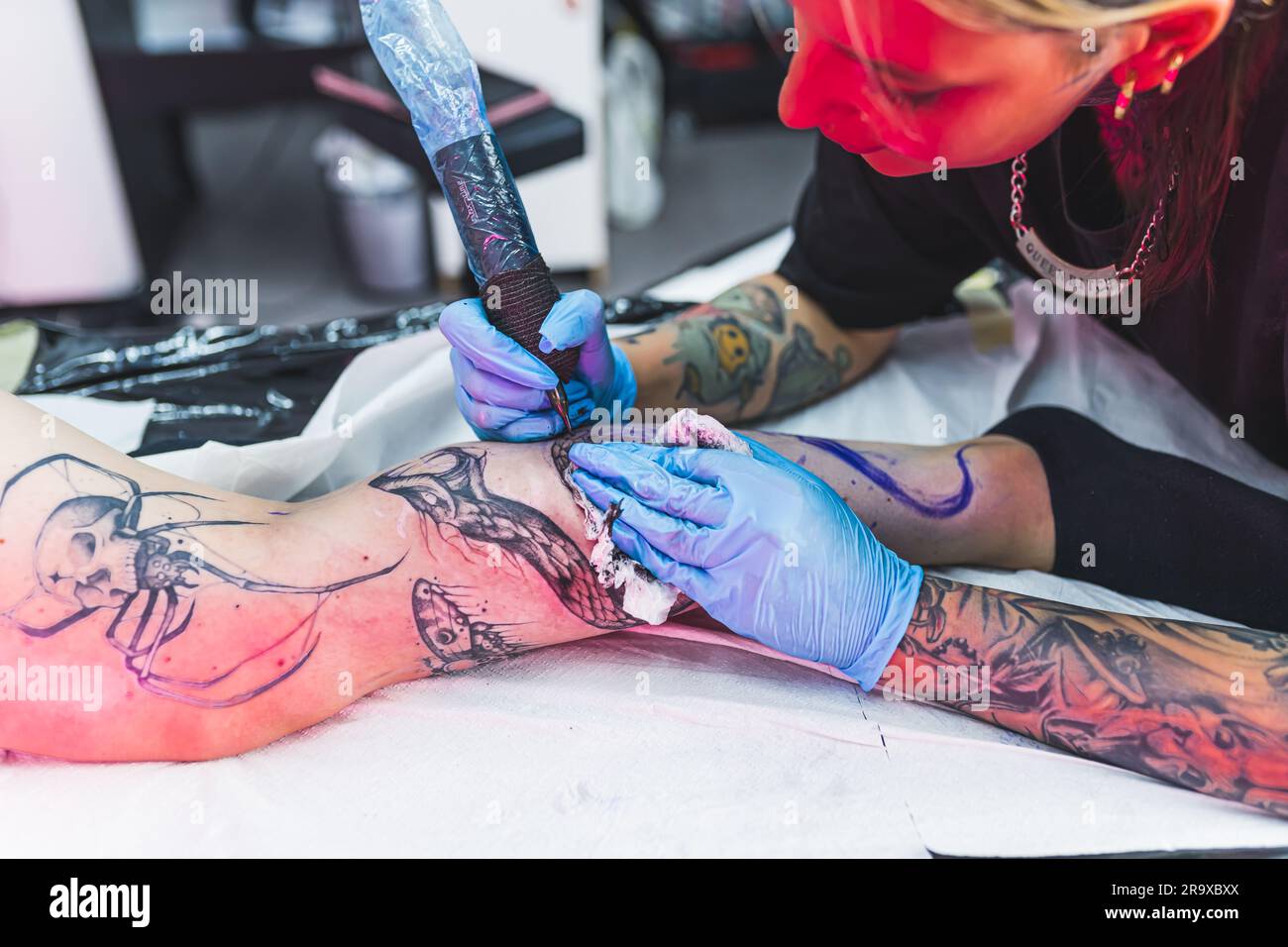 A professional tattoo artist makes a black and white tattoo on a woman ...