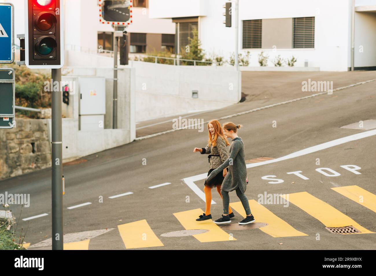 Young children crossing road, walking and chatting Stock Photo