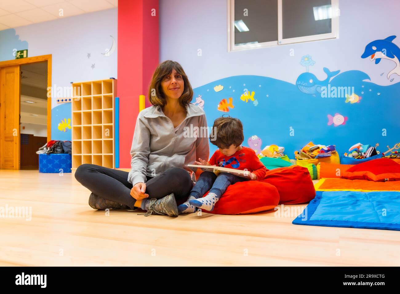 Portrait of a female teacher with a child sitting reading a story book ...