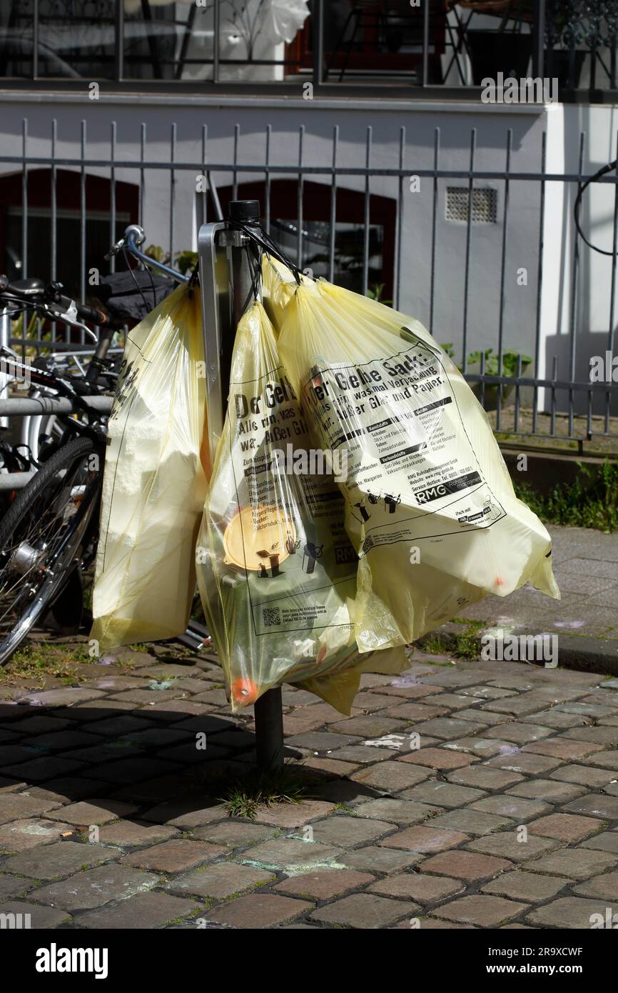 Yellow bags for plastic waste, hanging on a barrier on the street