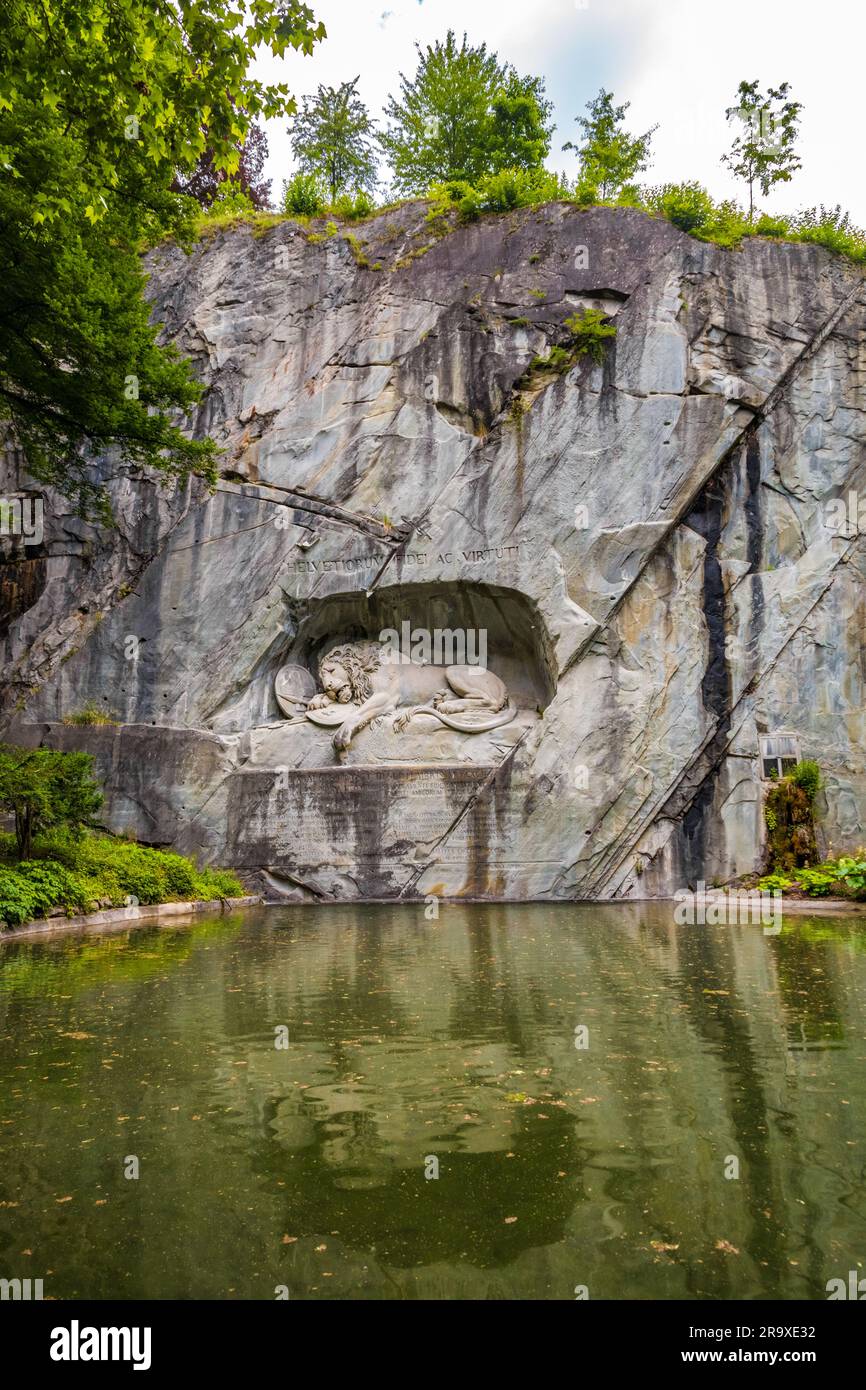 Great view of the famous lion monument, nestled in a rocky grotto in a charming park setting in Lucerne. The landmark can be seen as a commemoration,... Stock Photo