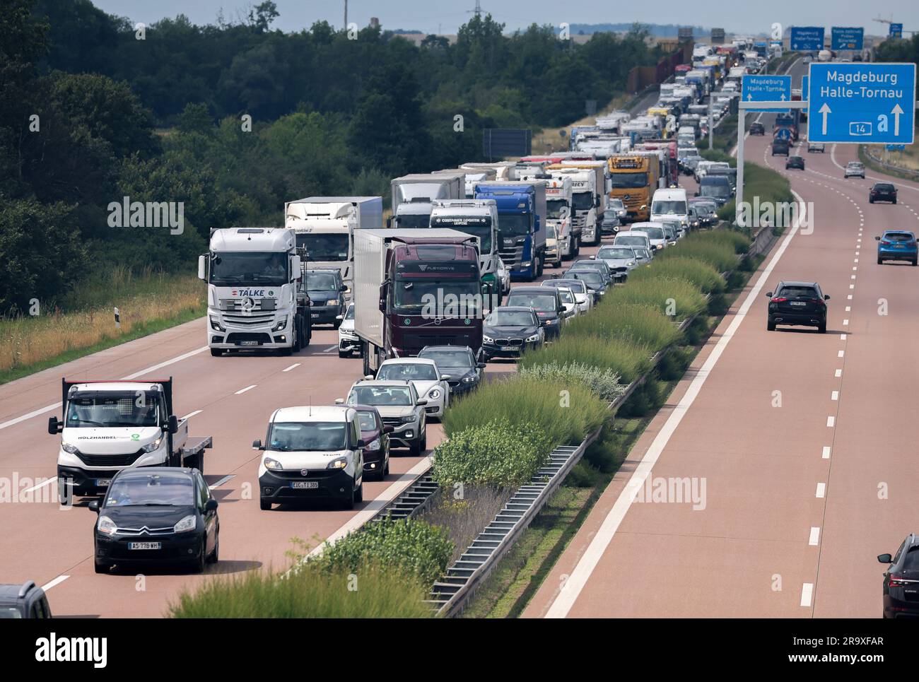 29 June 2023, Saxony-Anhalt, Halle (Saale): Cars and trucks are jammed on the A14 during a field fire. A fire had previously broken out in the field in the district of Reideburg. According to the police, the right lane of the highway 14 was closed not far from the fire site because of the massive smoke development. Photo: Jan Woitas/dpa Stock Photo