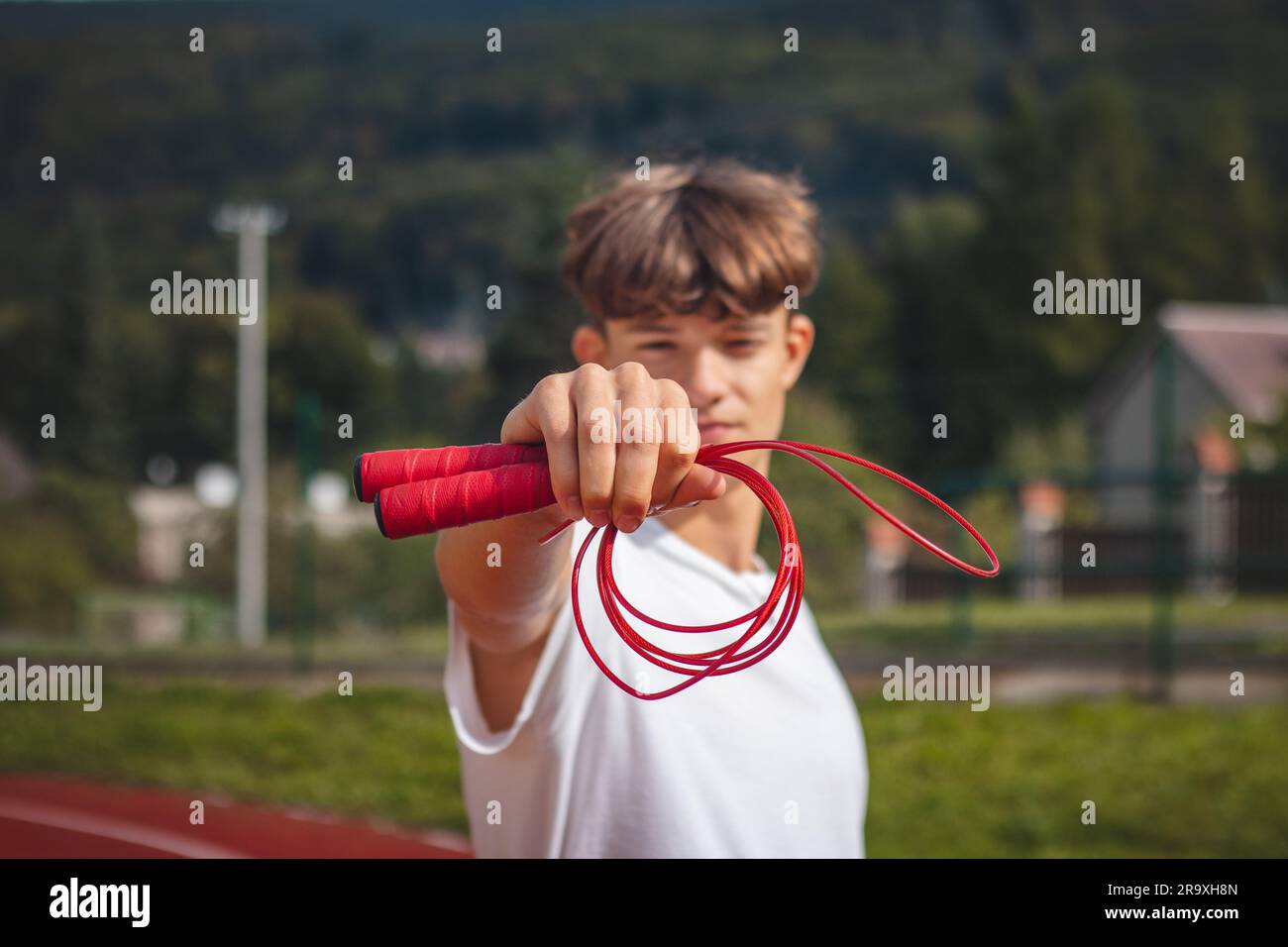 Brown-haired boy with an athletic build promotes the jump rope as one of the best tools for improving endurance, jumping power. Stock Photo