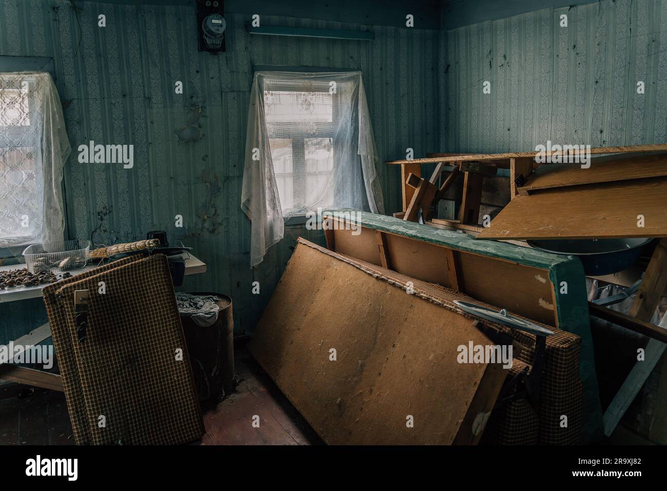 The room of an abandoned old village house with a pile of old broken furniture and other rubbish Stock Photo