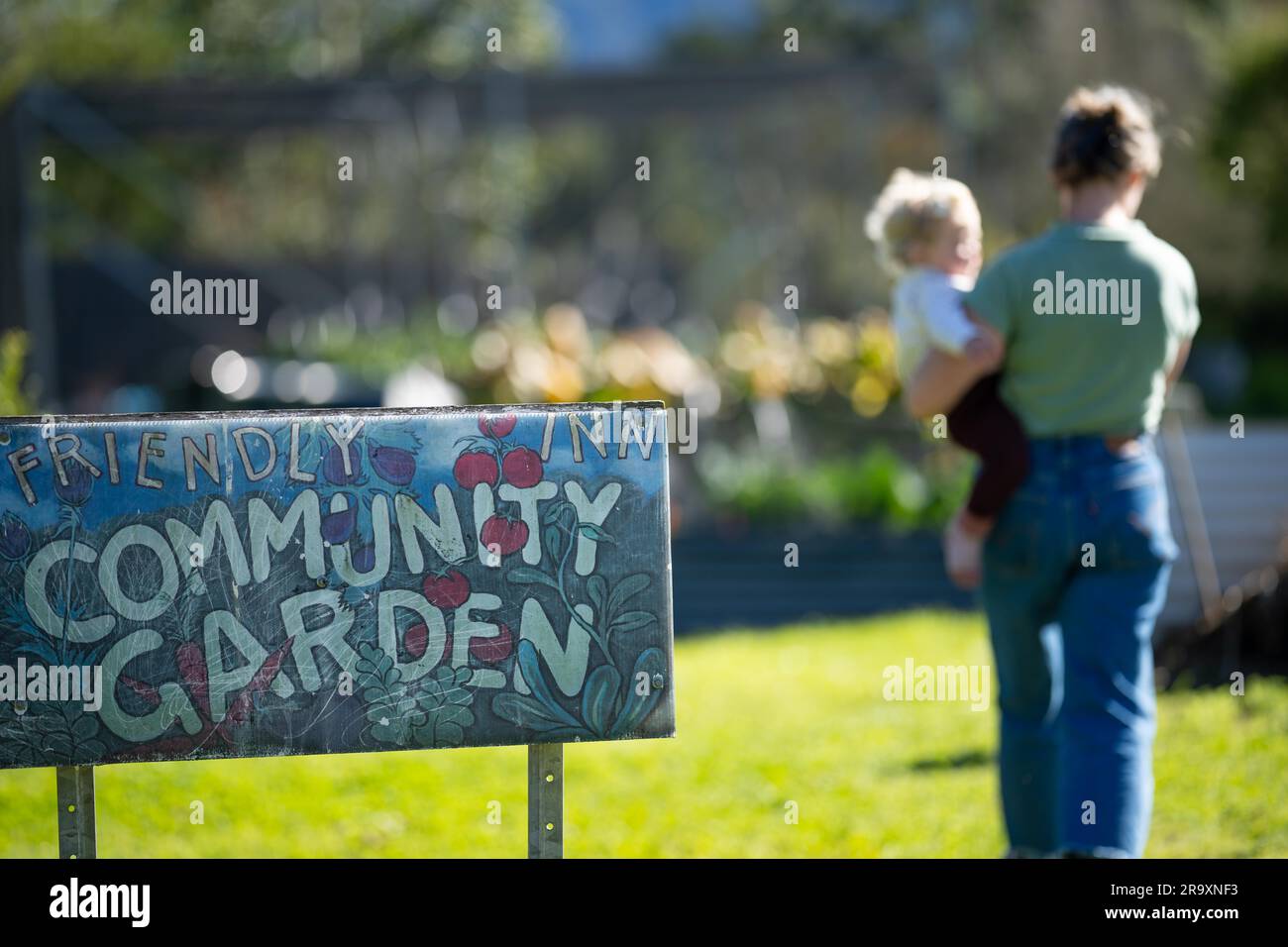 community garden sign at a vegetable garden with a mother and baby in a city garden in australia in spring Stock Photo