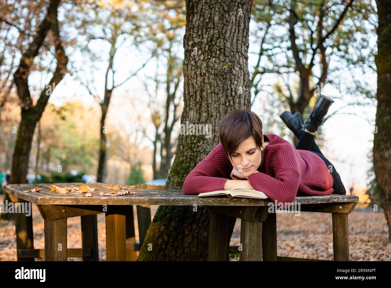 A young woman in the park lying on the bench, reading a book Stock ...
