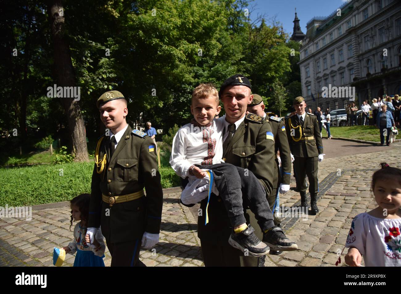 A cadet seen carrying a child in his arms during the celebration of the Constitution Day of Ukraine. Ukraine celebrated the 27th anniversary of the adoption of the country's basic law - the constitution. In the conditions of the Russian-Ukrainian war, official events were very short. In Lviv, the Ukrainian flag was raised, honor guard marched, and a military band performed. (Photo by Pavlo Palamarchuk / SOPA mages/Sipa USA) Stock Photo