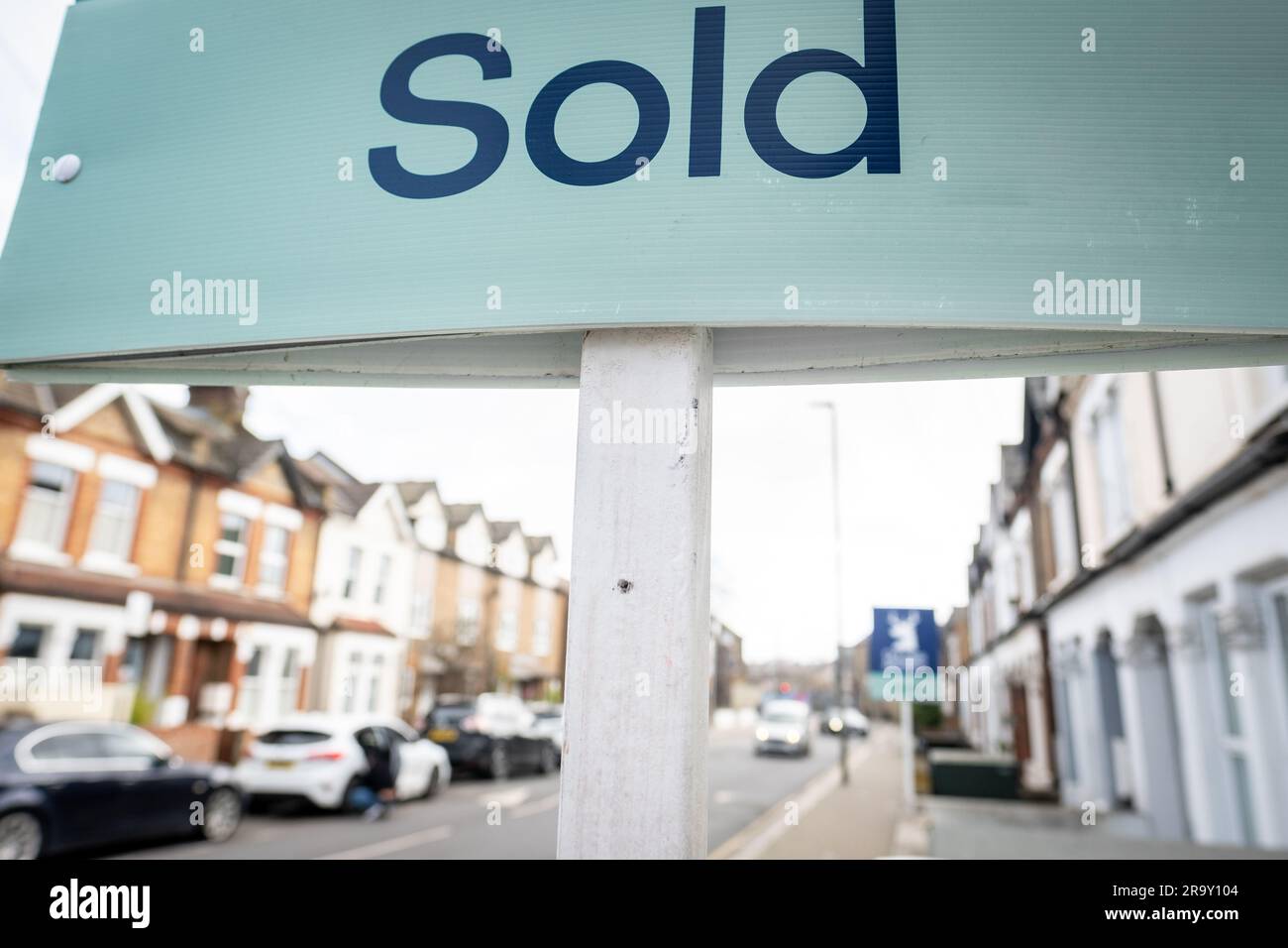 Estate agent SOLD sign with defocussed street of houses in background Stock Photo