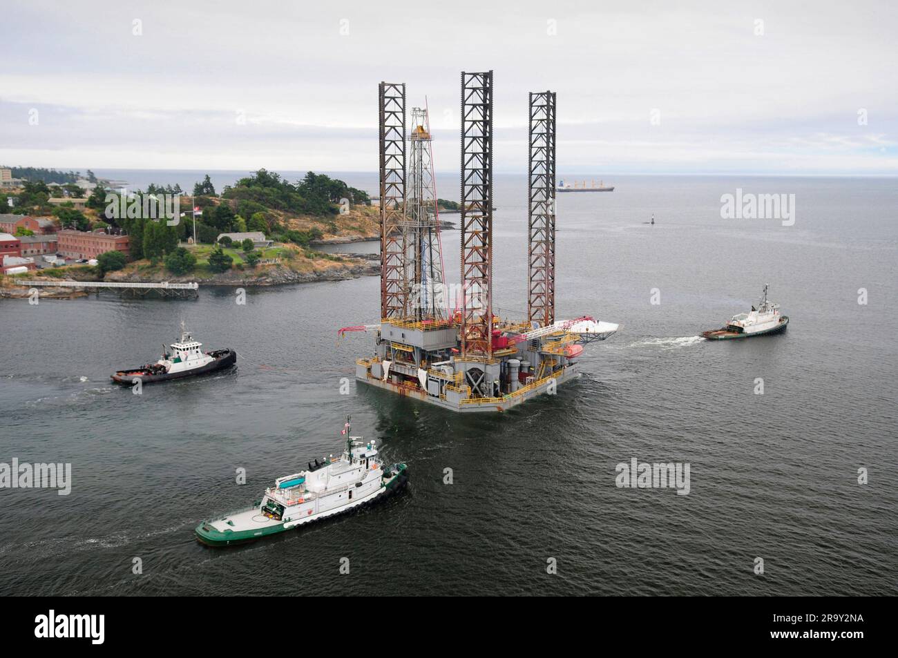 Aerial image of an oil drilling rig being towed out of port by three ...