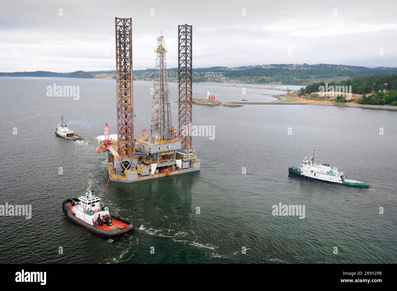Aerial image of an oil drilling rig being towed out of port by three ...