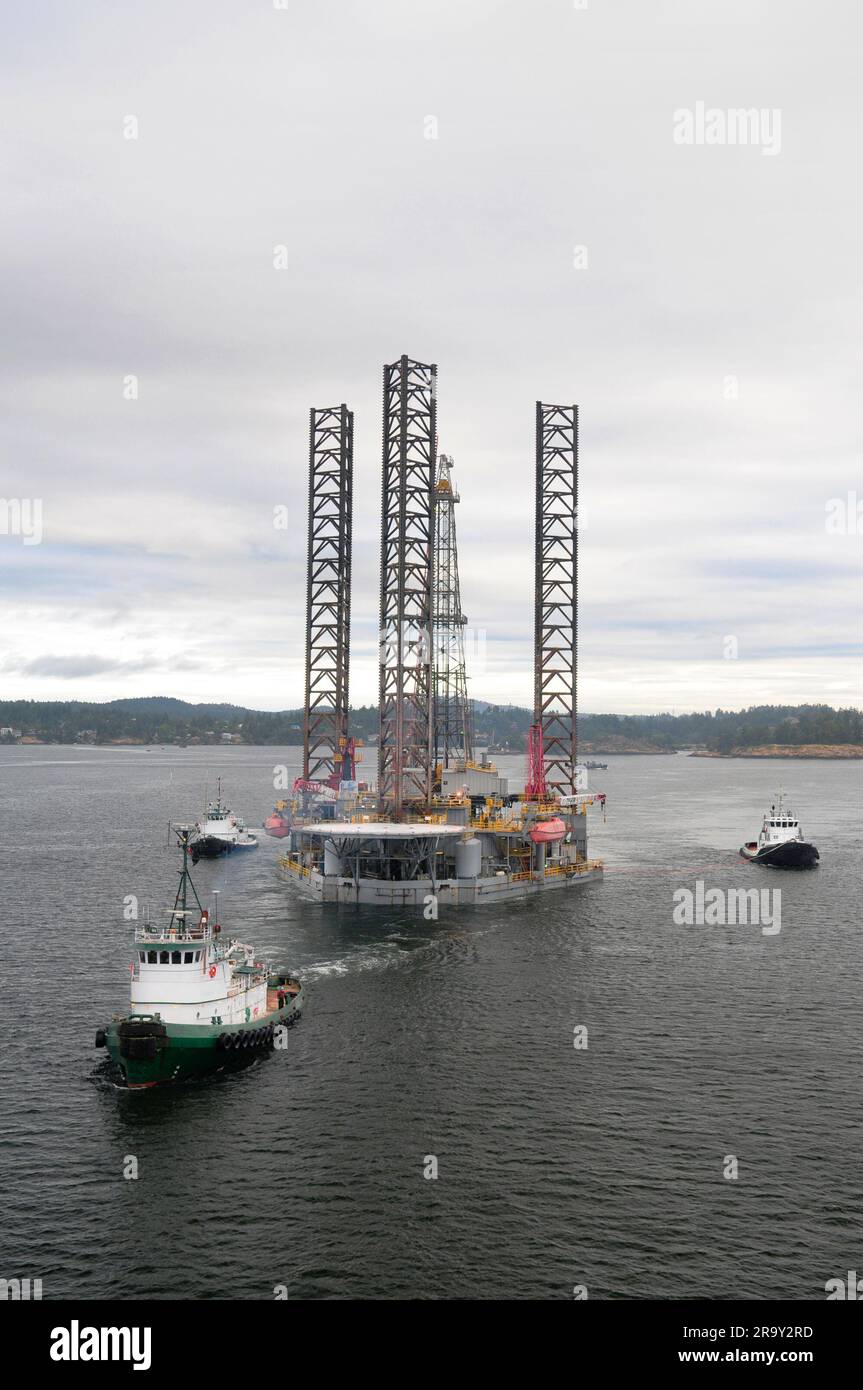 Aerial image of an oil drilling rig being towed out of port by three ...