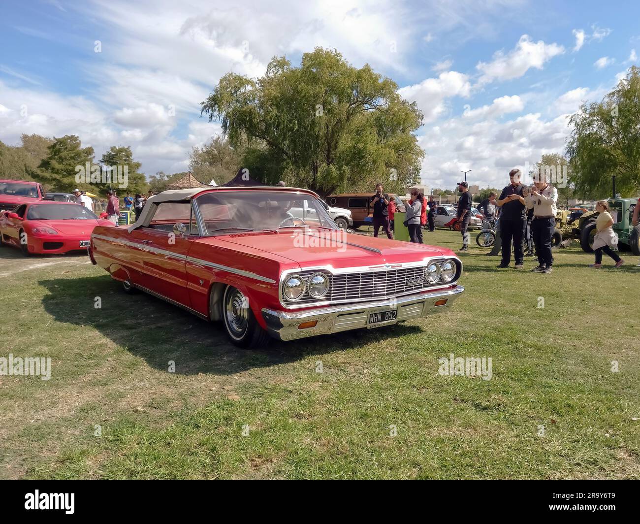 old popular red 1964 Chevrolet Chevy Impala SS Super Sport convertible on the lawn. Nature grass and trees. CAACMACH 2023 classic car show. Copyspace Stock Photo
