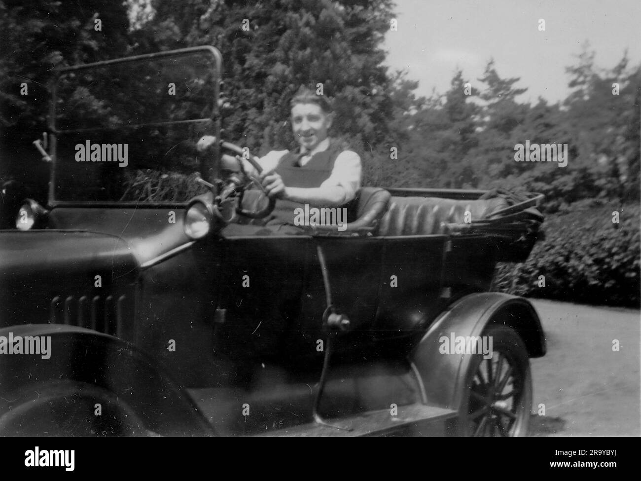 A man driving an open top car. Photo from a family album of snapshot images mainly taken in the UK, during the 1920s. The family lived in Witley, Surrey, and had some links to the military. Stock Photo