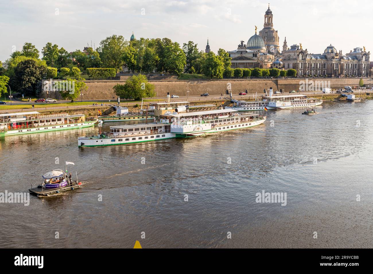 Modern and historical tourist fun on the Elbe. Party raft and paddle steamer in front of Elbe panorama with Dresden Frauenkirche. With nine historic paddle steamers, the White Fleet is the oldest and largest fleet of paddle steamers in the world. Dresden, Germany. Dresden on the Elbe River Stock Photo