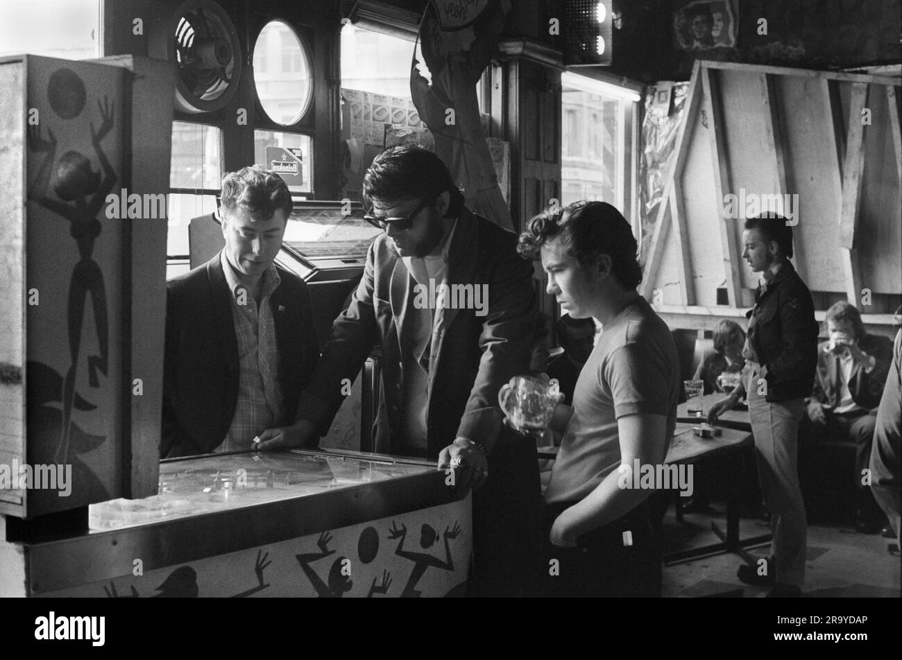Teddy Boys 1970s UK. Playing a pinball machine at The Black Raven in Bishopgate Street, 'Sunglasses Ron Staples', styled himself the 'King of the Teds' the 'Edwardian Teddy Boy'. (Sunglasses Ron Staples, died in 1999.) Moorgate, London, England 1975.  1970s UK HOMER SYKES Stock Photo