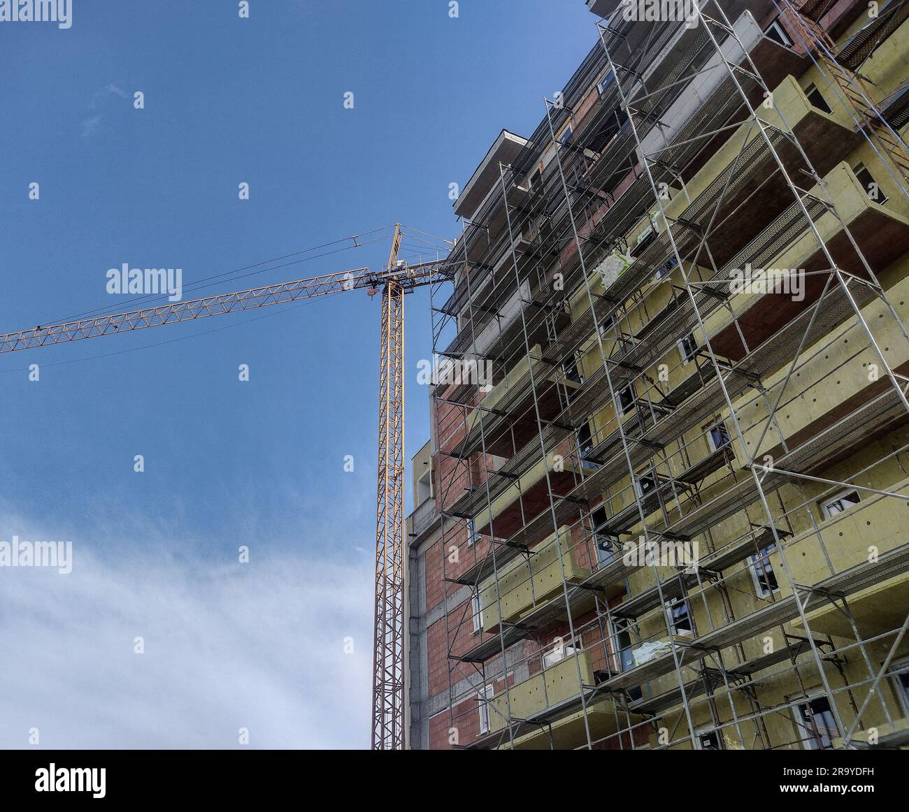 A building during construction and a crane next to it. Construction ...