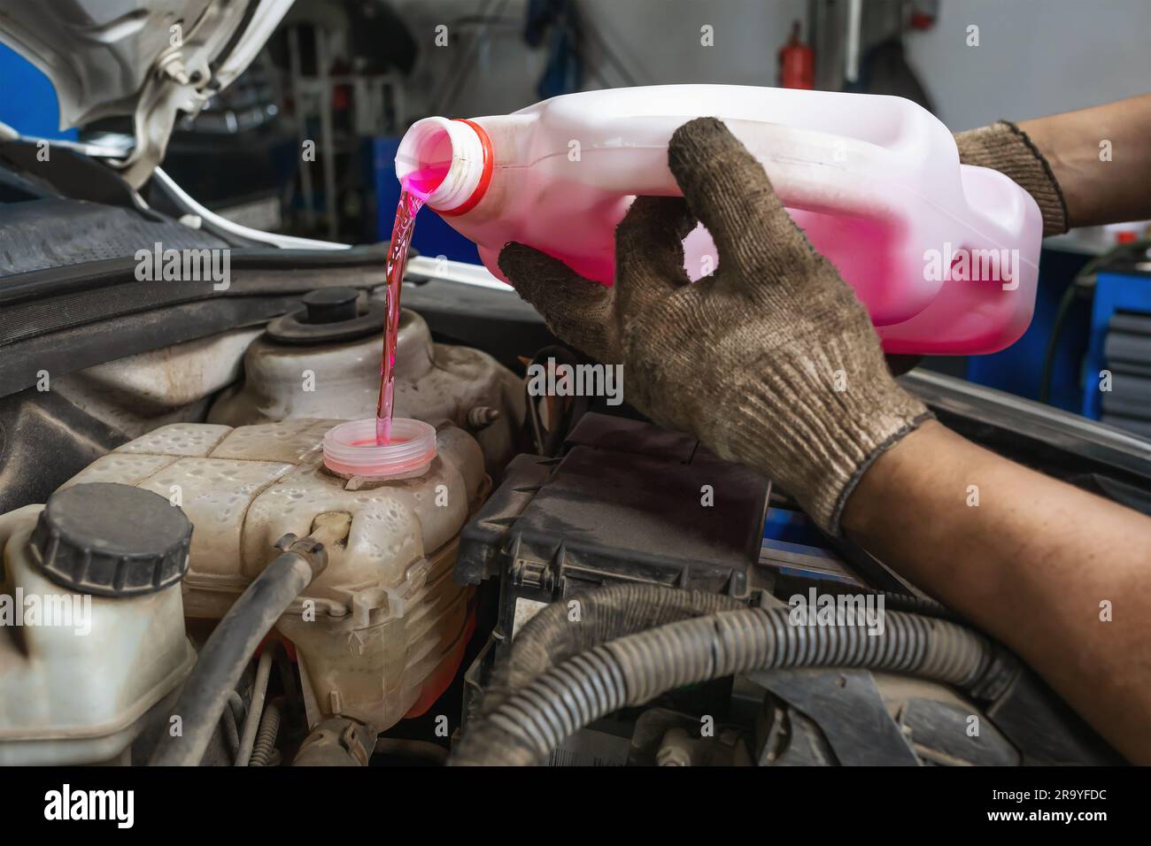 An auto mechanic at a service station pours antifreeze into the ...
