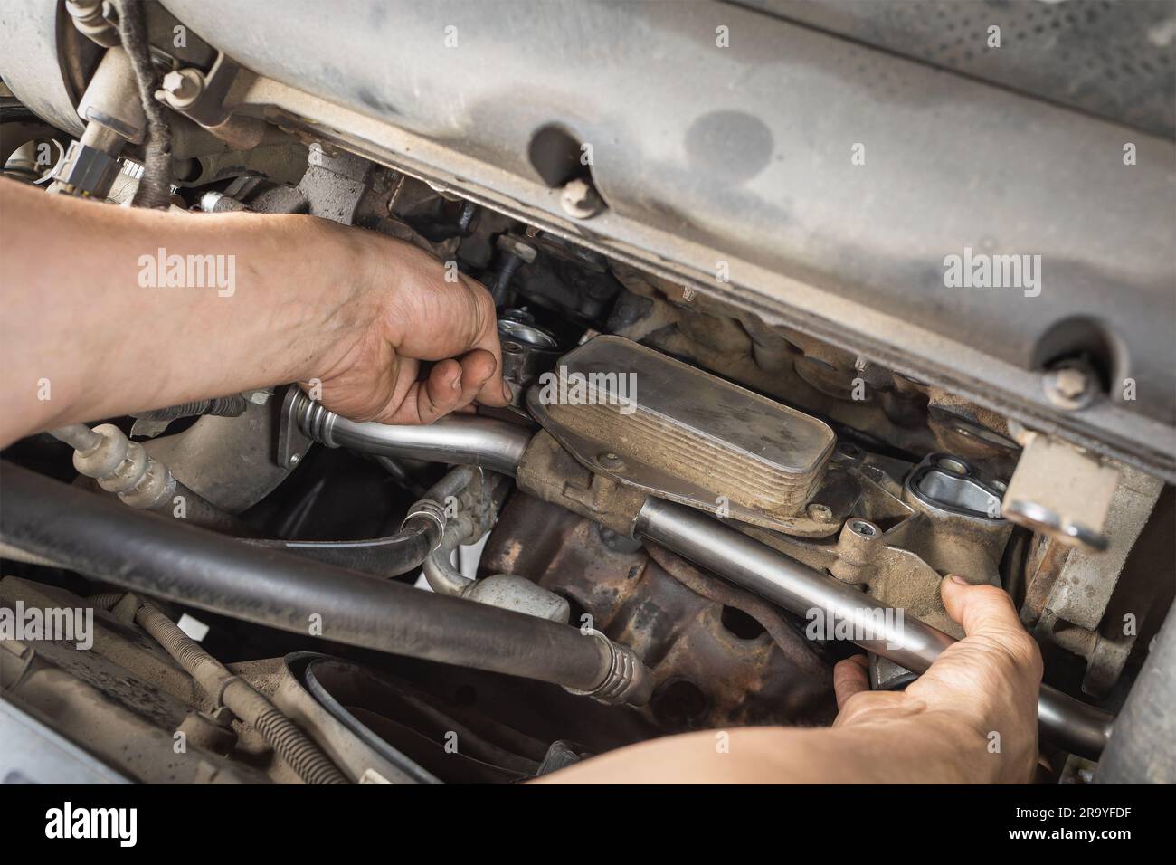 Auto mechanic installs a heat exchanger for a gasoline engine of a passenger car, post-warranty service at a technical inspection station Stock Photo