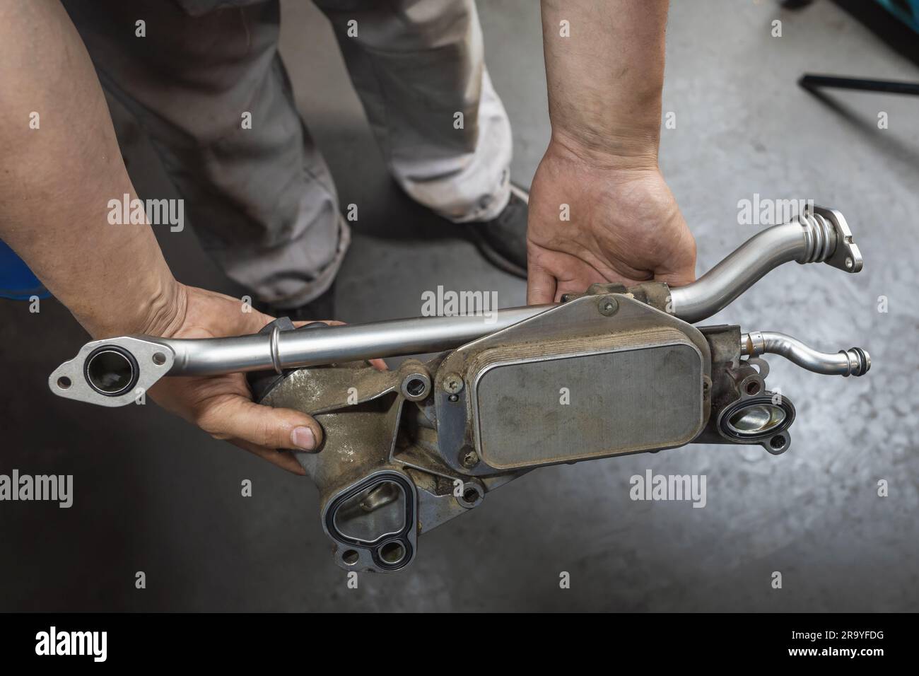 An auto mechanic holds in his hands a heat exchanger for a gasoline engine of a passenger car with cleaned tubes and new gaskets, post-warranty servic Stock Photo