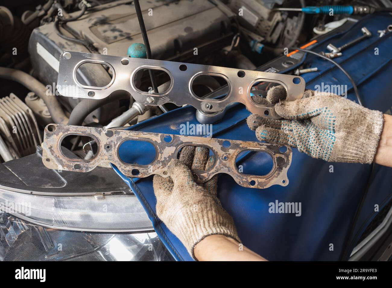 Auto mechanic holding old and new manifold gaskets for passenger car
