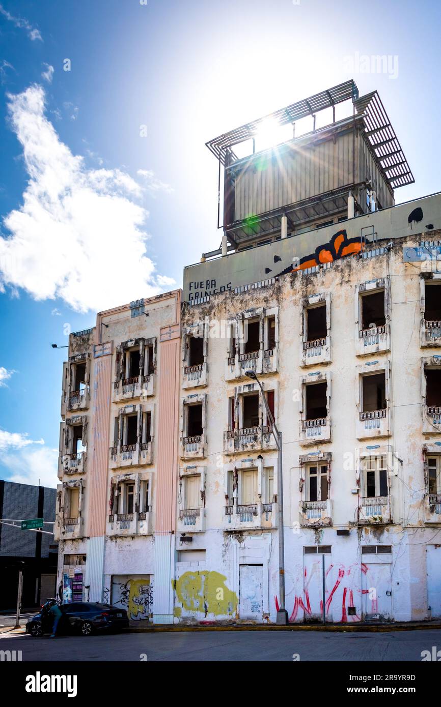 San Juan Puerto Rico abandoned apartment building in ruins near Centro de Bellas Artes, peeling paint, no windows, sunburst shining through structure. Stock Photo