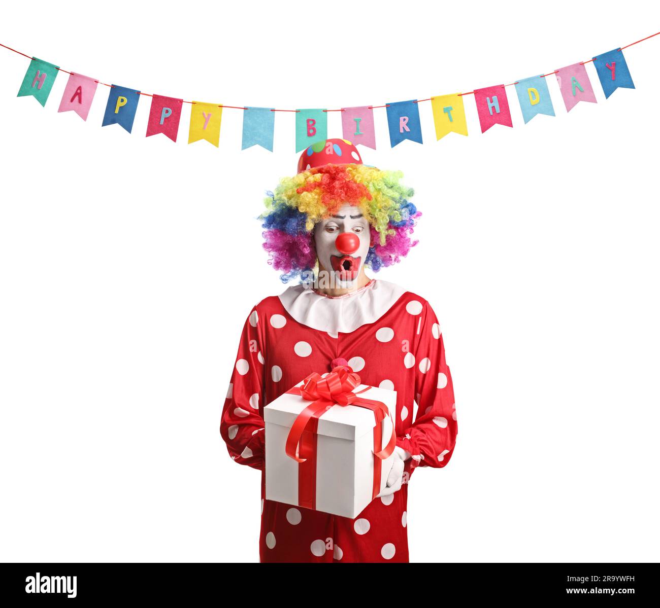 Surprised clown in a red costume holding a present box isolated on white background Stock Photo