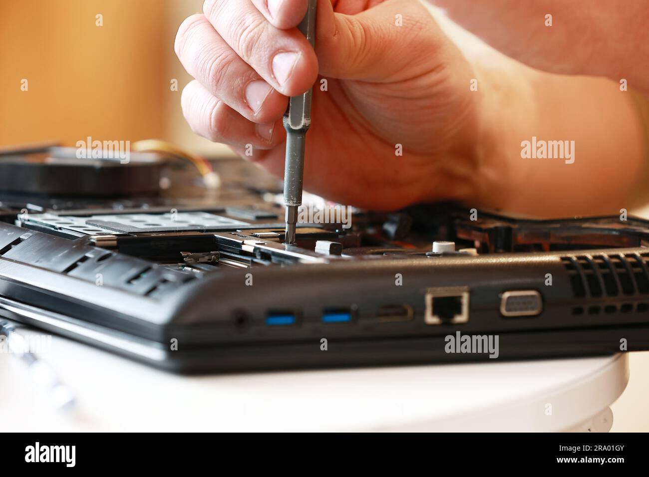Repaiman with screwdriver fixing disassembled laptop parts. Technical