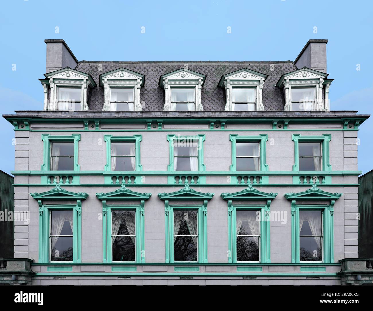Old apartment building with mansard roof and ornate frames around windows Stock Photo