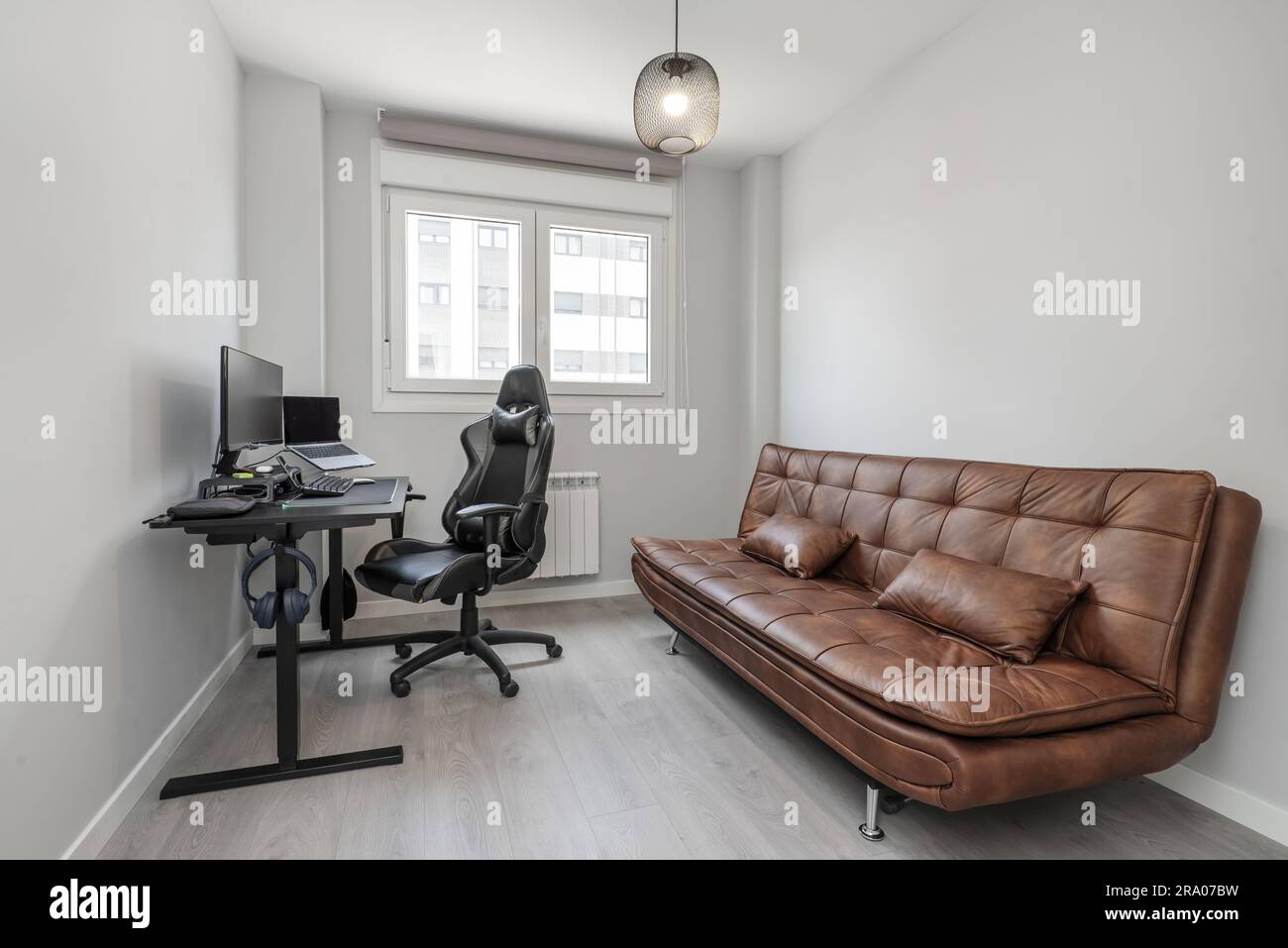 Room with brown leather folding sofa bed and desk with gaming pc or workstation Stock Photo Alamy